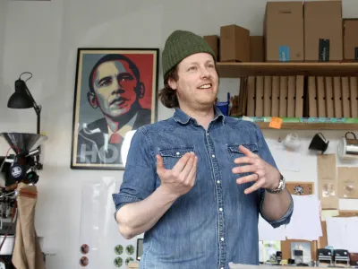 En mann på en kafé som forklarer om kaffe. Et bilde i bakgrunnen.