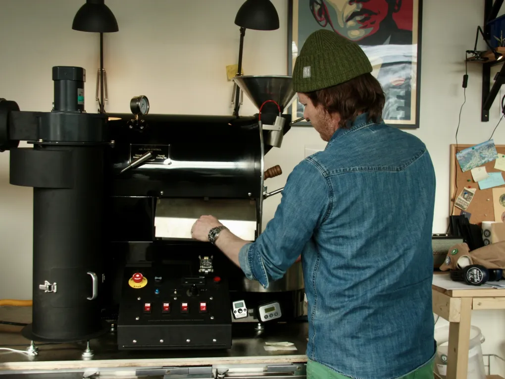 En mann på en kafé som lager kaffe med en kaffemaskin.