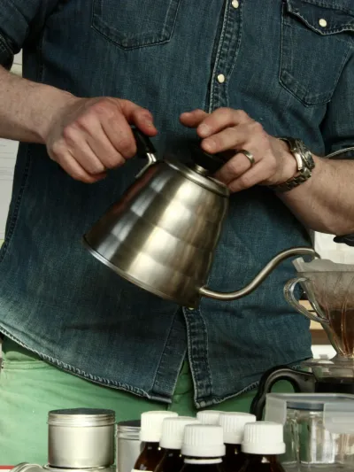 Mann som heller kokende vann over malt kaffe.