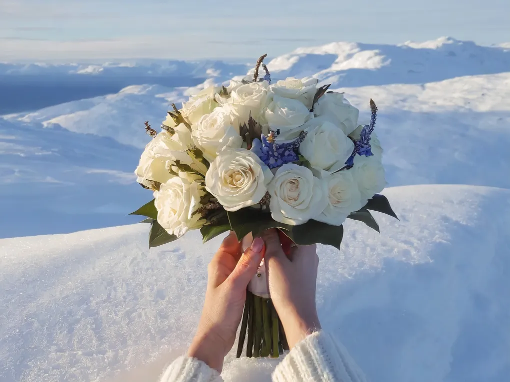 Nærbilde av hender som holder en bukett med blomster