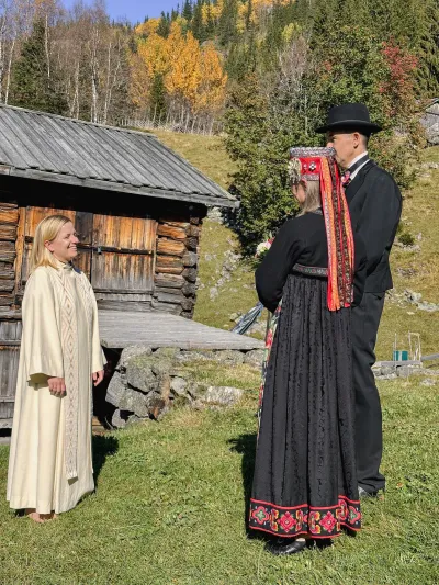 Mennesker på gårdstun. Natur og gammel bygning i bakgrunn