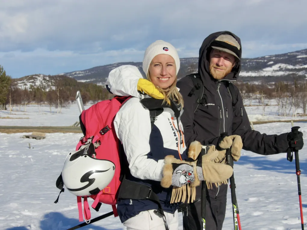 To mennesker som smiler, og er ute i solen på vinteren