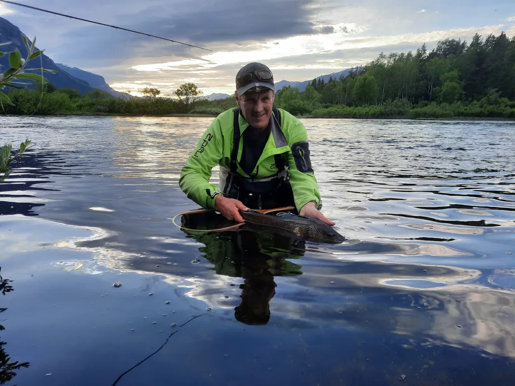 Mann i vannet som nettopp har fanget en fisk