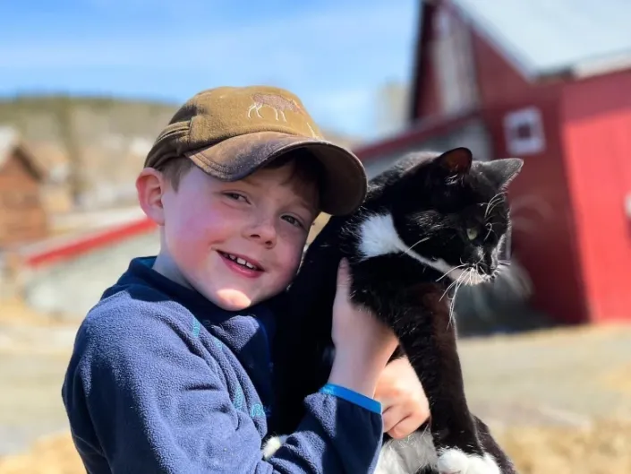 Nærbilde av en gutt som holder en svart-hvit katt