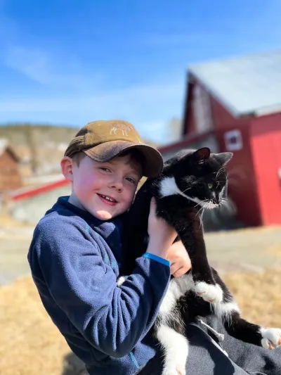 Nærbilde av en gutt som holder en svart-hvit katt