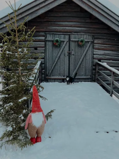 Bilde av en låve med et tre og en liten nisse på vinteren