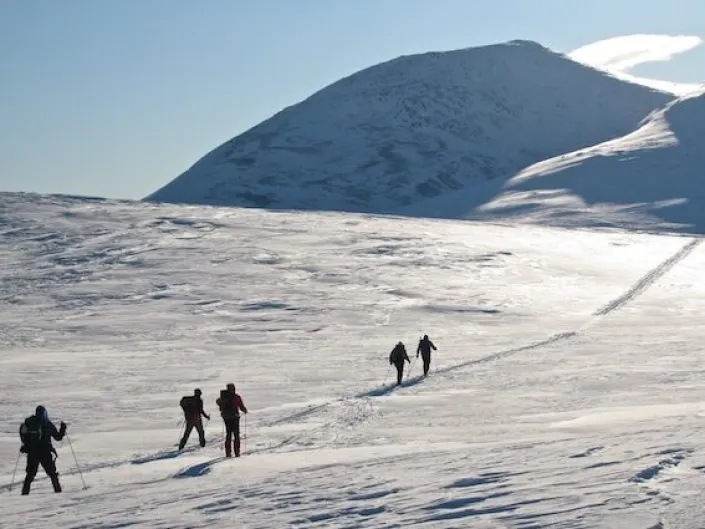 Topptur bilde fra avstand, med mennesker som går oppover i fjellet.