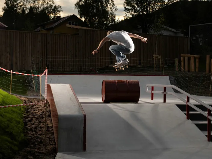 Mann som hopper over en tønne med skateboard.
