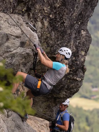En dame og en mann som klatrer Via Ferrata