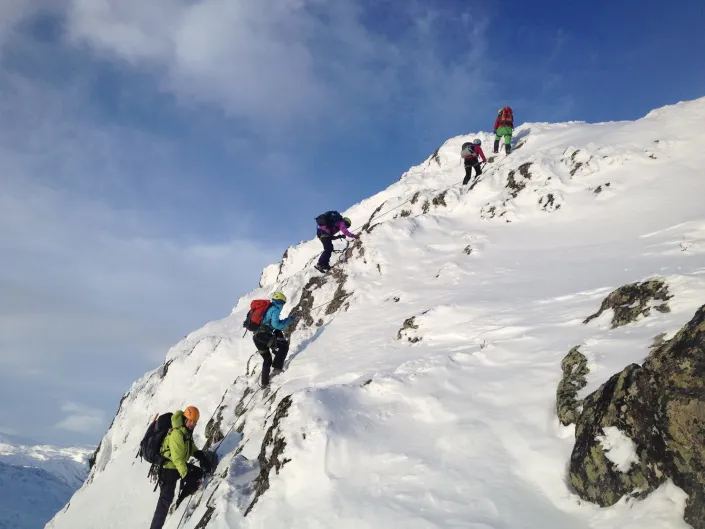 Gruppe mennesker som går på viaferatta på snødekkede fjell.