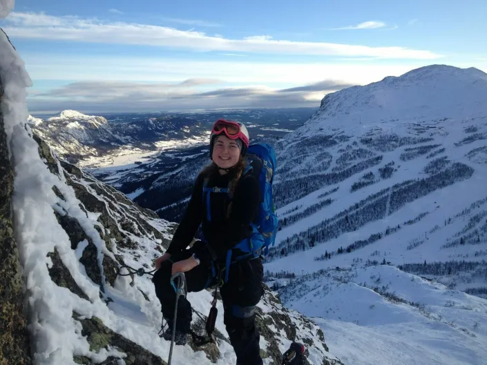 Dame som går viaferrata om vinteren, i bakgrunnen er det fjellene/skisenteret.