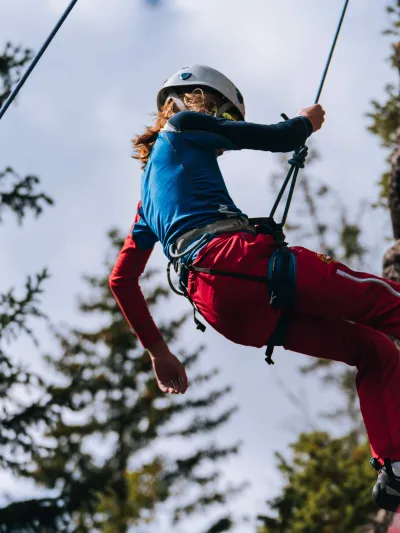 En jente som rapullerer ned fjellveggen