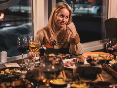 Dame som nyter tapas og vin rundt et bord.