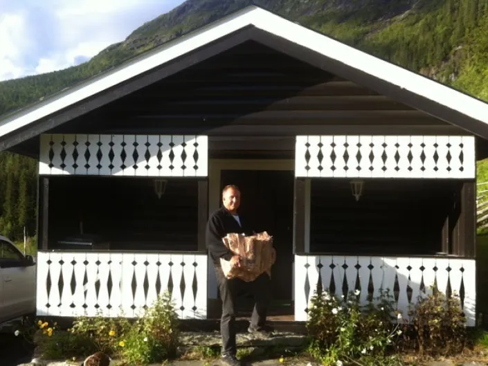 Mann som bærer ved inn i en hytte