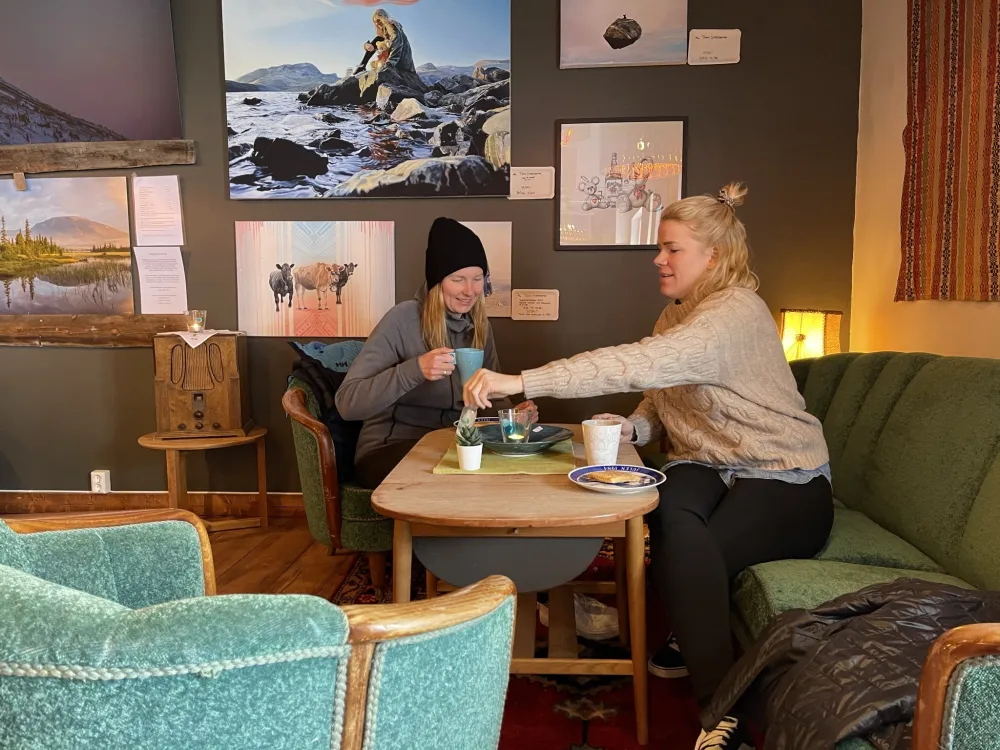 To damer som sitter ned og koser seg med kvikaku og kaffe.