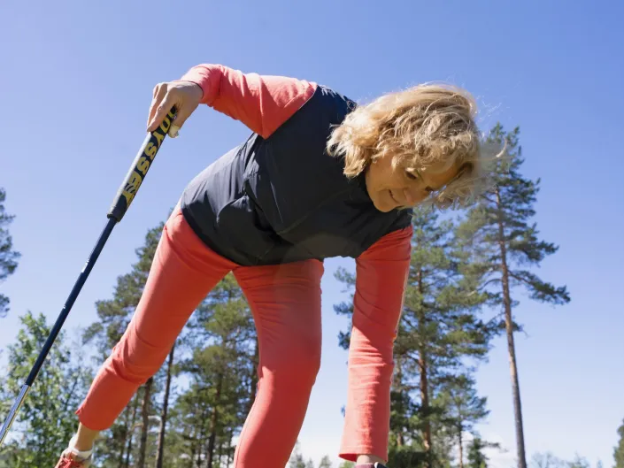 Dame som bøyer seg ned for å plukke opp en golfball