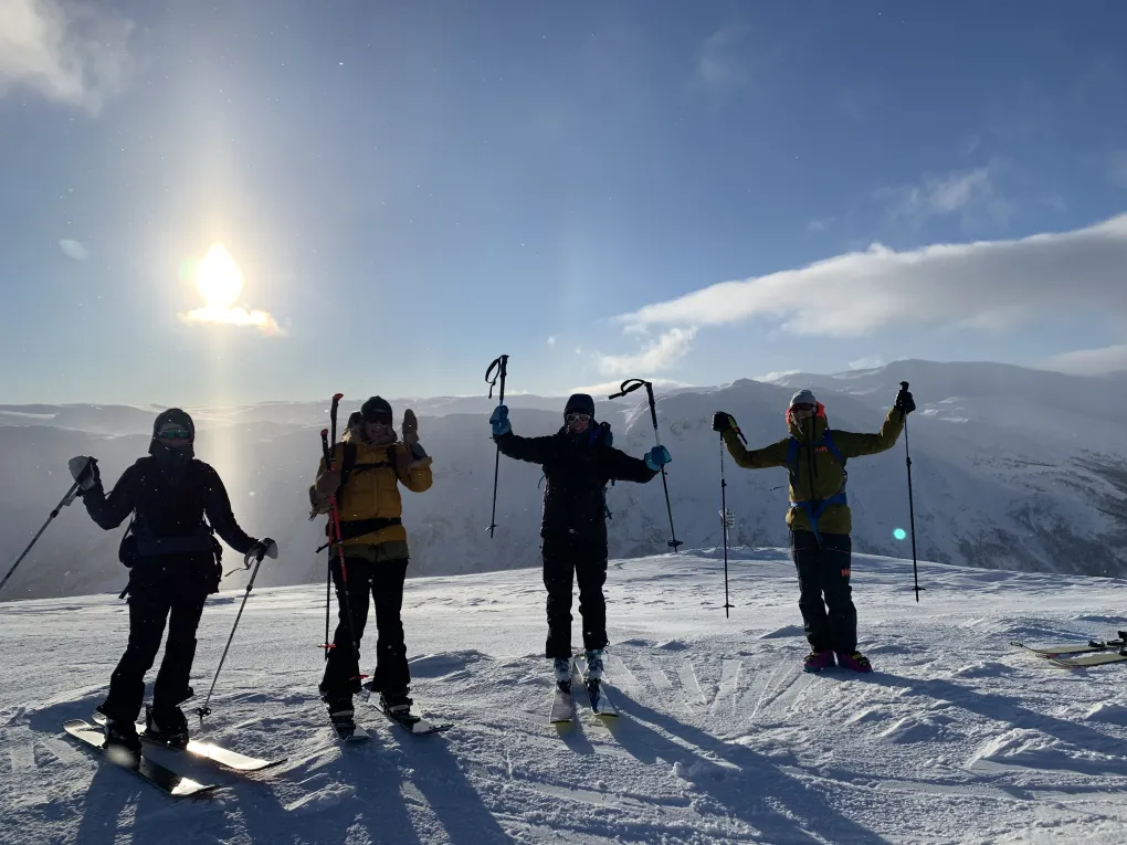 Fire damer på toppen av fjellet, rundt dem blåser det.