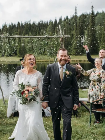 To mennesker som har giftet seg smiler mens de går mot kamera