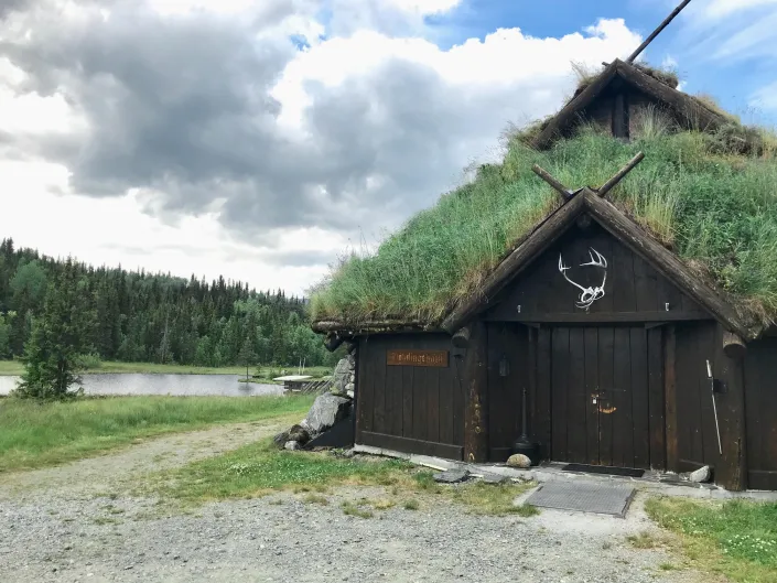 Et bilde av et gammelt hus med gress på taket