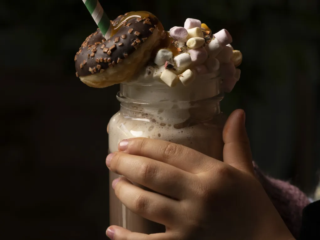 Nærbilde av en kakao med krem med dougnut