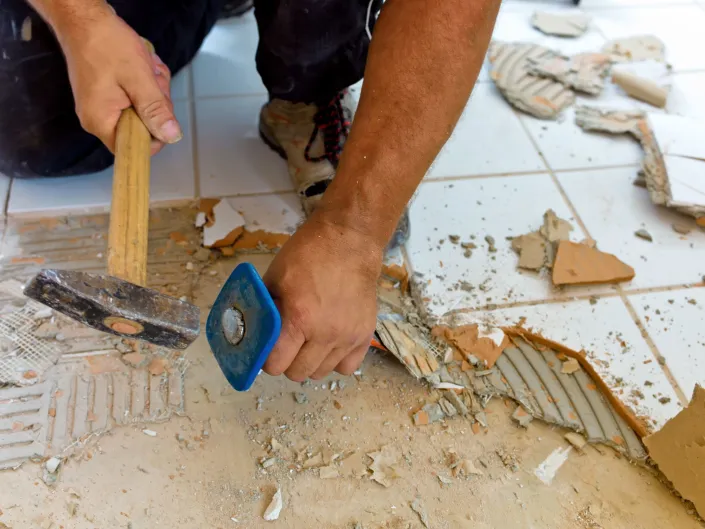 Mann som hakker opp gammelt baderomsgulv