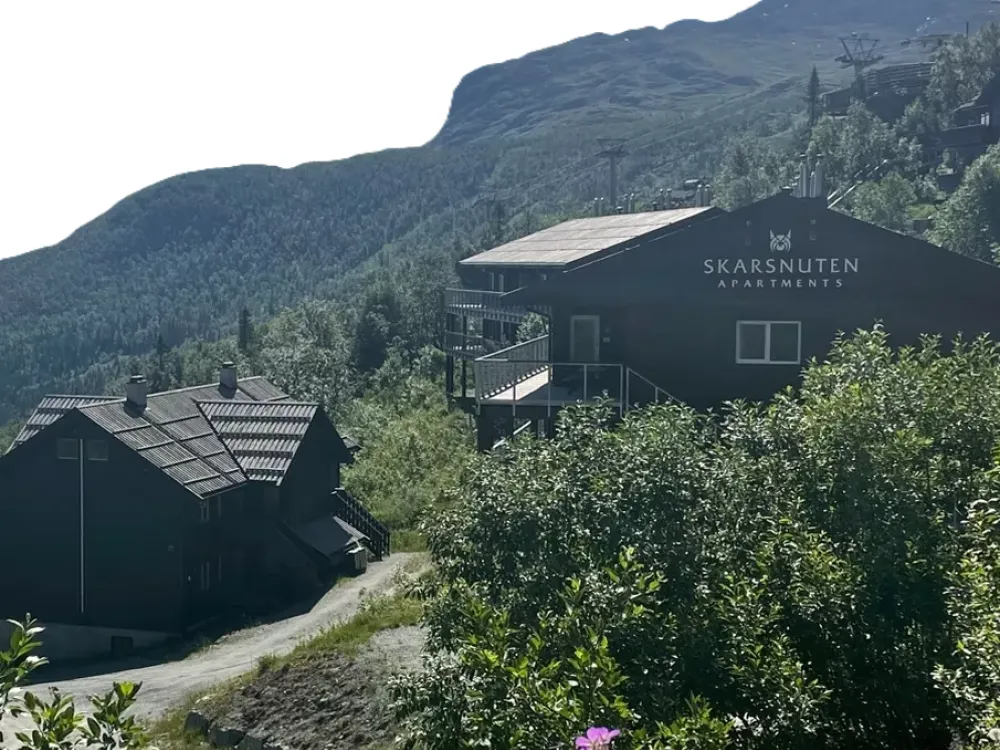 Leiligheter i svart med skriften skarsnuten apartments på sommerstid.