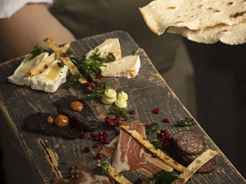 Jørgen som holder et fat med spekemat, lefser og forskjellige oster.