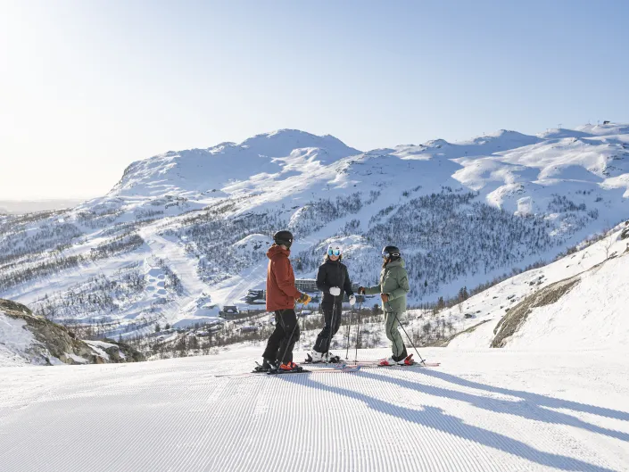 Tre personer står med ski på i skiløypa i SkiStar Hemsedal