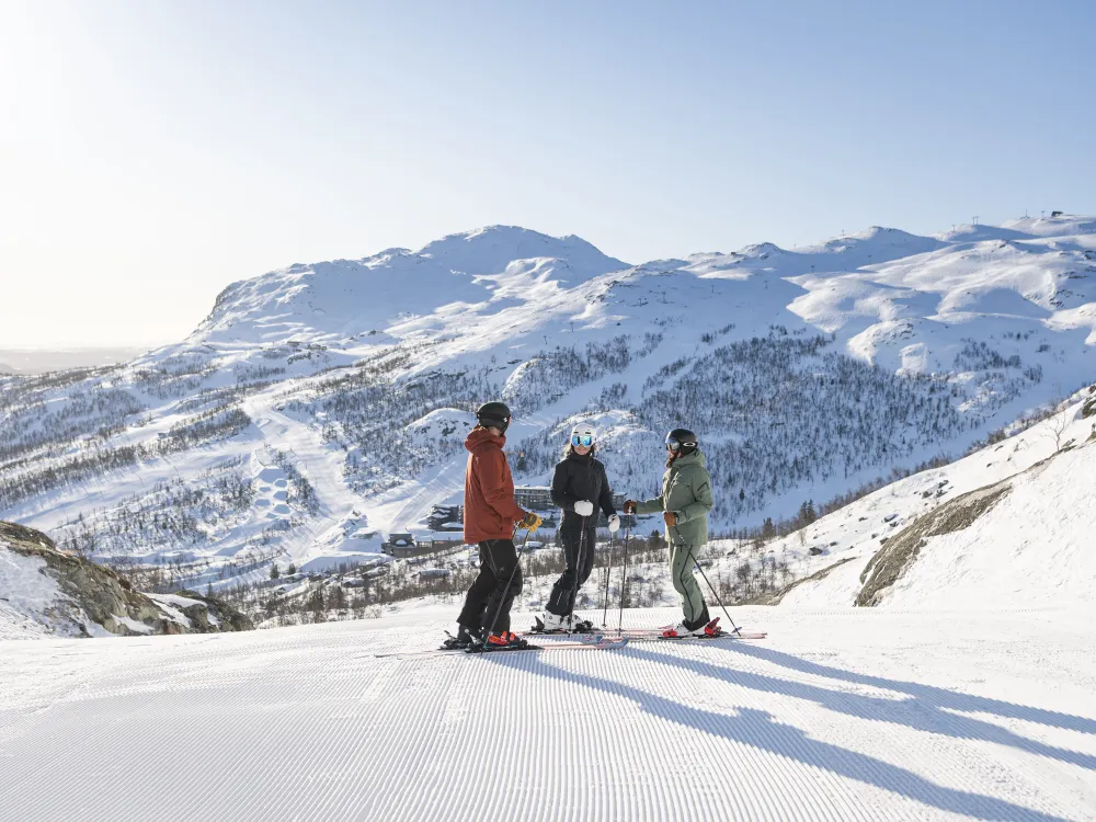 Tre personer står med ski på i skiløypa i SkiStar Hemsedal