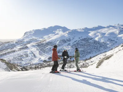 Tre personer står med ski på i skiløypa i SkiStar Hemsedal