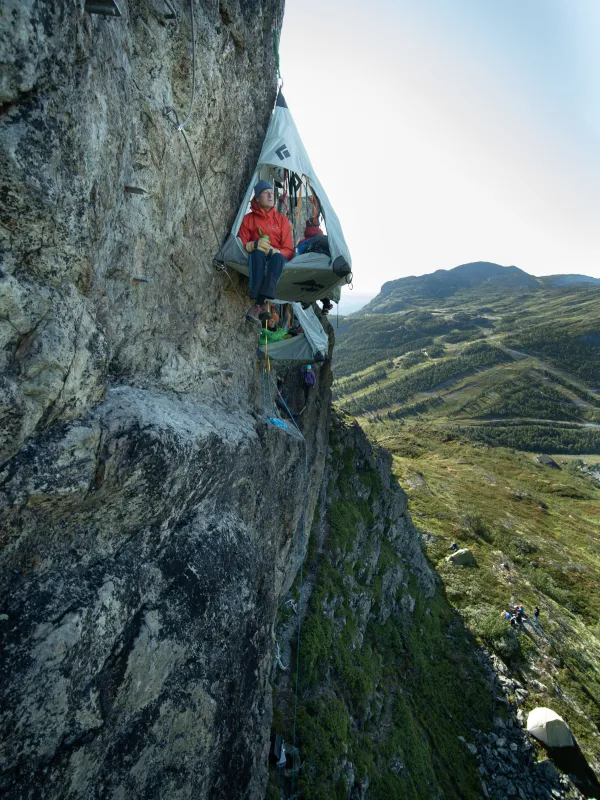 Avstandsbilde av skysleeping, og en mann som har beina ut av et av telt.