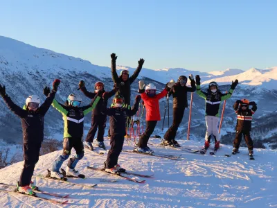 Gruppe mennesker som holder armene er været og står på slalom i solheisen Hemsedal