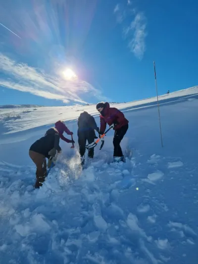 Bilde til skredkurs 2022, mennesker som graver i snøen, og i bakgrunnen er det sol og fint vær.