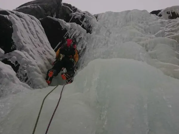 Nærbilde av en som isklatrer i en foss.