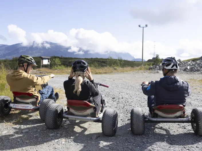 Tre personer som sitter på hver sin mountain cart.