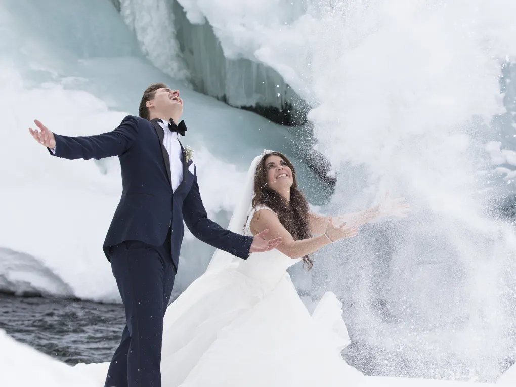 Mann og dame som akkurat har giftet seg, og kaster snø opp i luften.