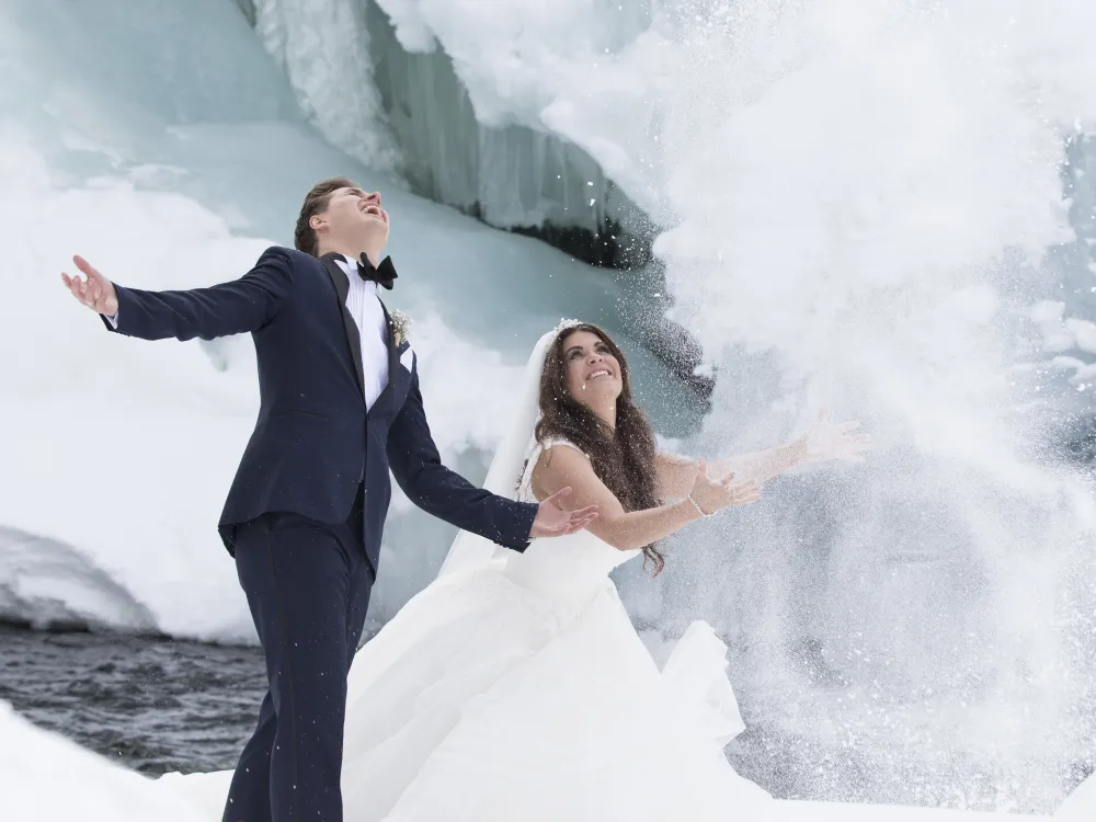 Mann og dame som akkurat har giftet seg, og kaster snø opp i luften.