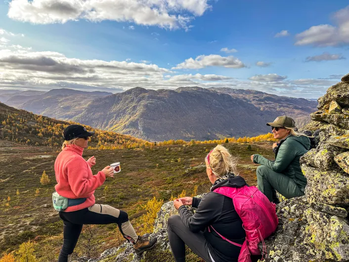 Tre mennesker tar seg en pause ved varde på fjellet i Hemsedal