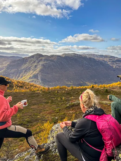 Tre mennesker tar seg en pause ved varde på fjellet i Hemsedal
