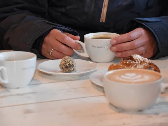 Bilde av tre kopper kaffe, en kanelbolle og en småkake
