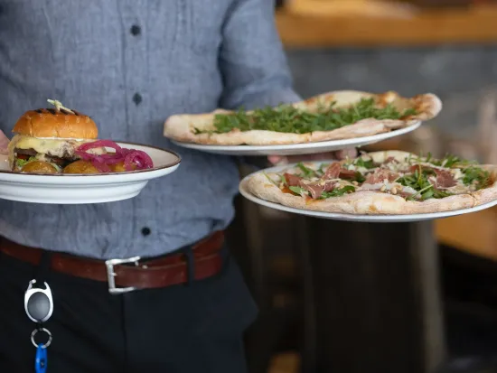 To pizza og en burger som en kelner kommer med.