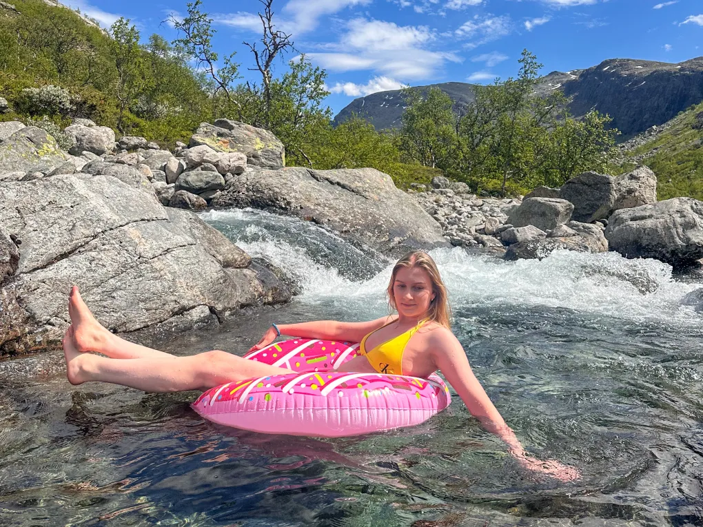 Dame som sitter i en donut i elva (sommer).