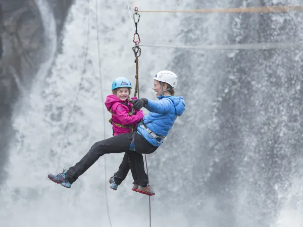 Mor og datter som kjører zip line ved en foss i Hemsedal