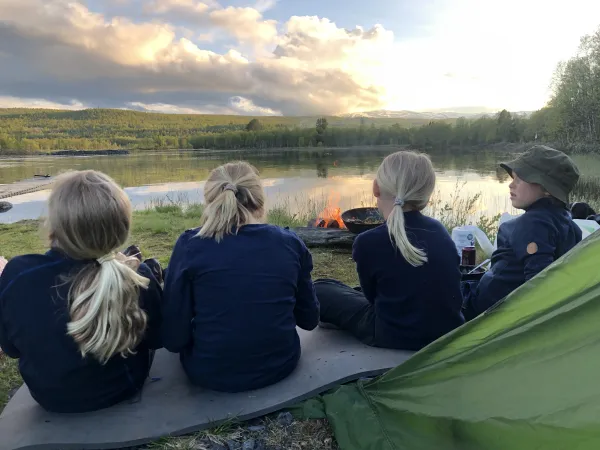 Fire barn som sitter foran et bål