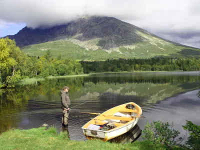 Mann som vasser i vannet med en gul båt ved siden av seg