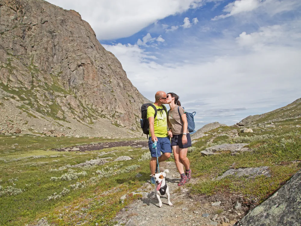 Kyssing i fjellet, hund er også med og fjell i bakgrunnen.