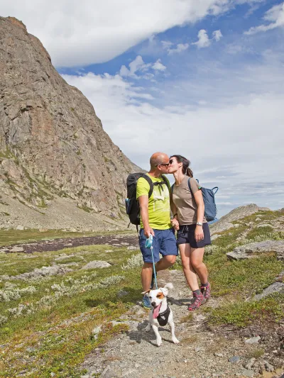 Kyssing i fjellet, hund er også med og fjell i bakgrunnen.
