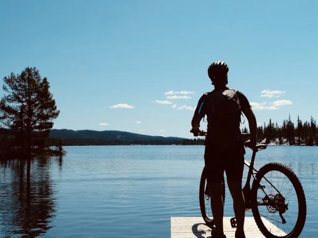 Mann som står på bryggen med sykkelen sin