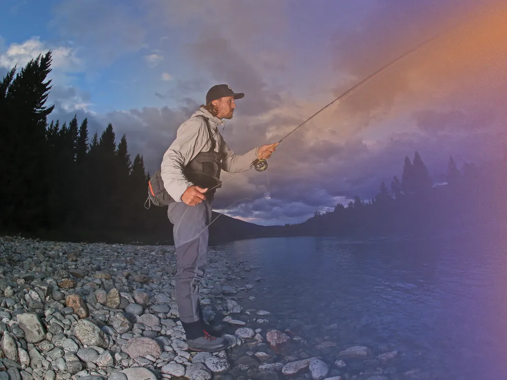 En mann som står og fisker i elva.