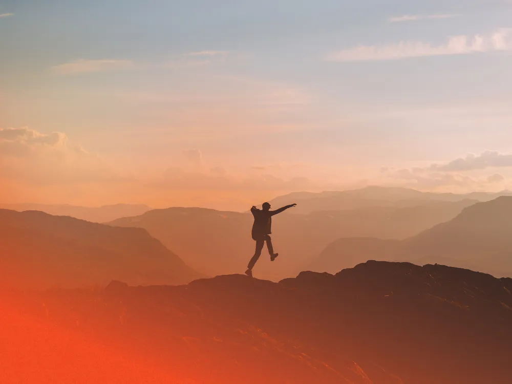 En mann som hopper av glede på fjelltur.